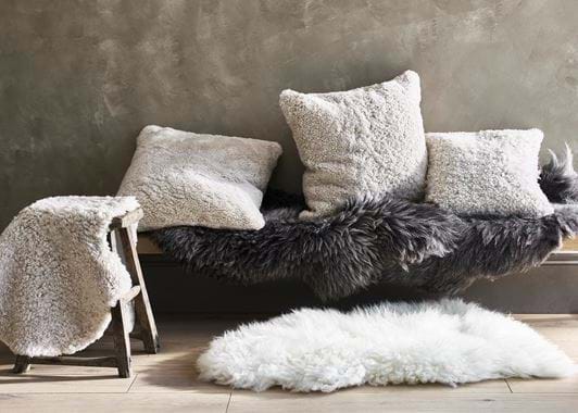 Sheepskin throws, rugs and cushions on bench